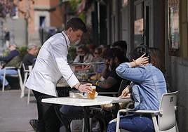 Un camarero sirve una cerveza en una terraza.