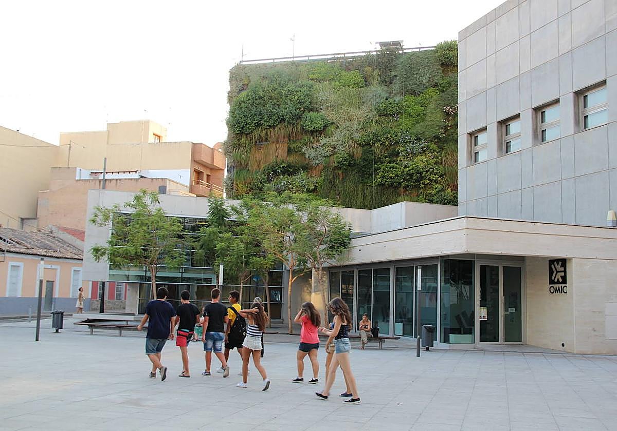 Un grupo de jóvenes pasea frente a la biblioteca municipal.