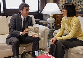 El presidente de la Generalitat, Carlos Mazón, recibe el libro obsequio de la secretaria general del PSPV, Diana Morant, en el Palau de la Generalitat.