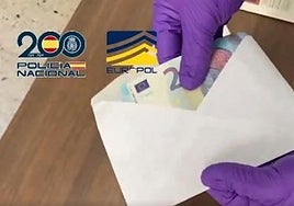 Un policía abre uno de los sobres enviados por la organización con los billetes falsos.