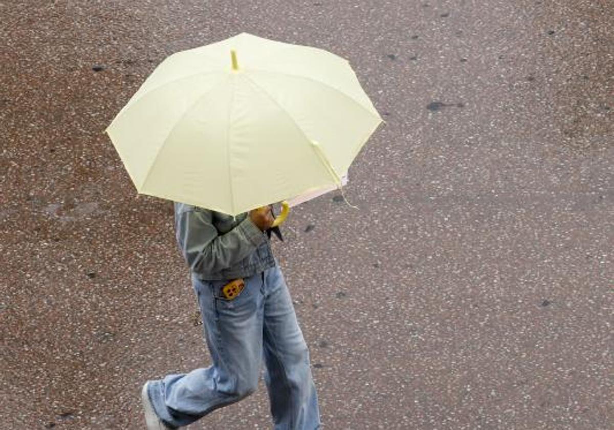 Un transeúnte se protege de la lluvia con un paraguas.