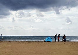 Un grupo de niños disfruta de la playa en un día nublado.