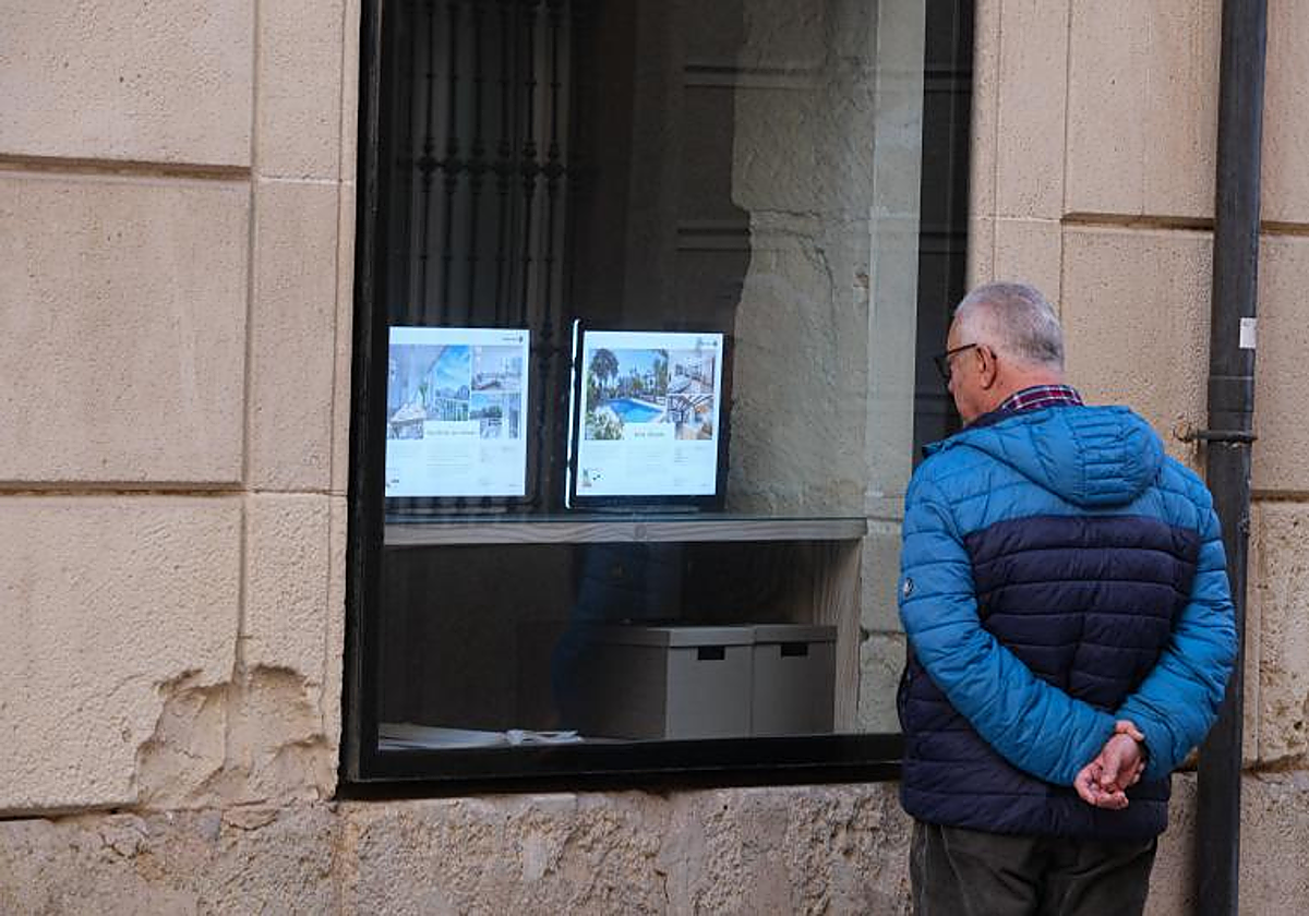 Un hombre consulta anuncios de pisos de una inmobiliaria de Alicante.