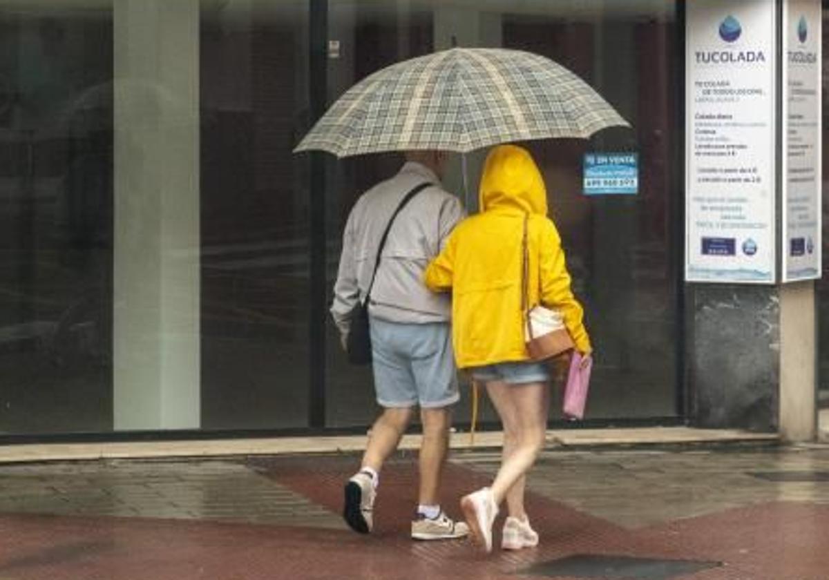 Una pareja pasea bajo la lluvia en Alicante.