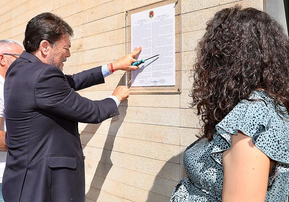 El alcalde de Alicante, Luis Barcala, coloca el bando municipal en la puerta del Ayuntamiento, en presencia de la concejal de Fiestas, Cristina Cutanda.
