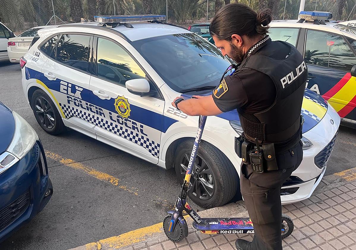 Un agente de la Policía Local, junto al patinete sustraído.
