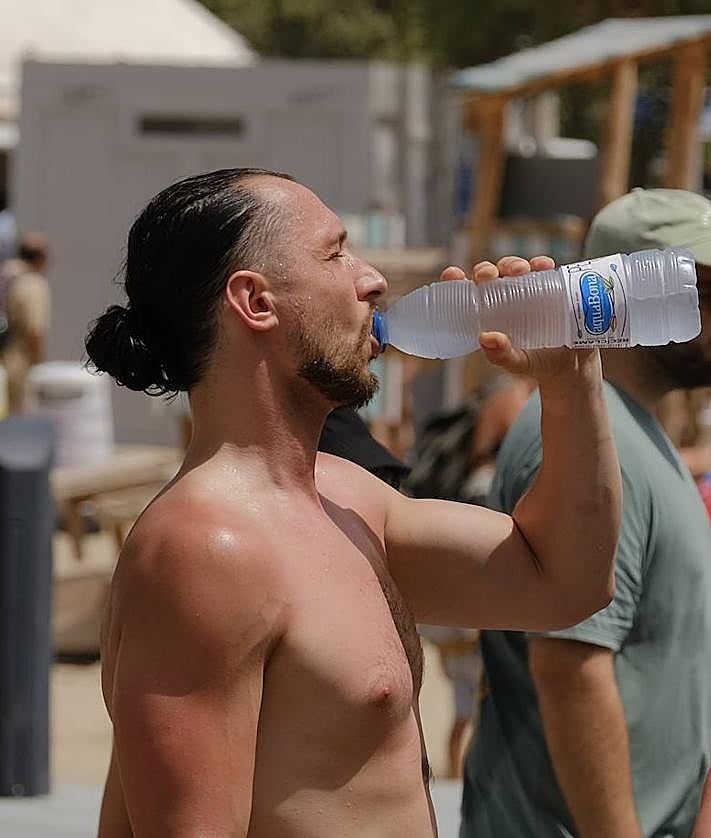 Imagen secundaria 2 - 1. El termómetro que marca la temperatura en la playa del Postiguet. 2. Un hombre rellena su botella de la fuente de agua fría del arenal alicantino. 3 Una persona bebe agua para refrescarse. 