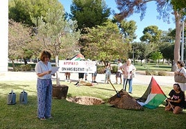 La rectora de la UA, Amparo Navarro, en su discurso antes de plantar el olivo, con la protesta al fondo.