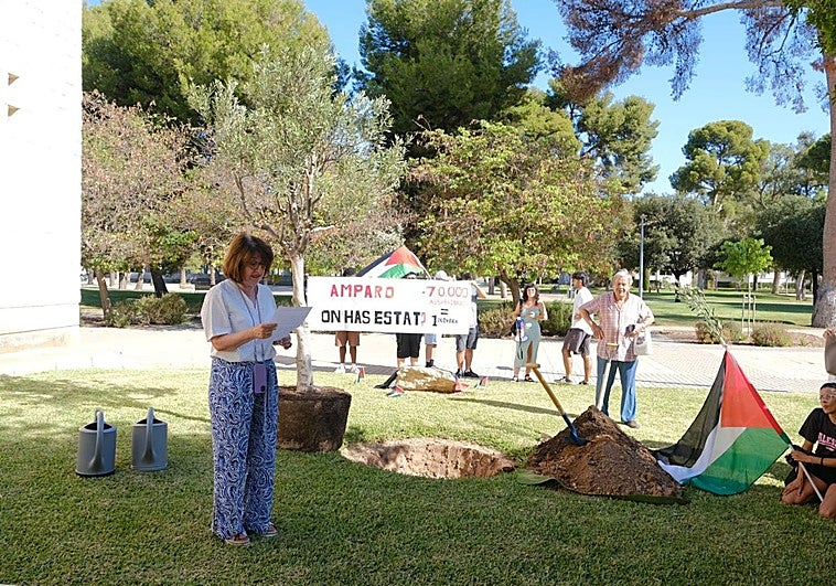 La rectora de la UA, Amparo Navarro, en su discurso antes de plantar el olivo, con la protesta al fondo.