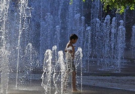 Un niño se refresca en la fuente de la plaza de España, frente a la plaza de toros de Alicante.