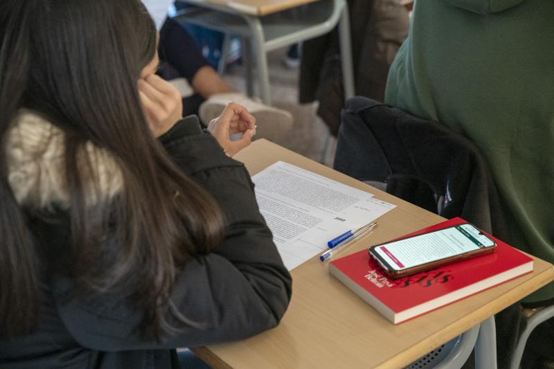 Una joven en una clase prestando atención a lo que lee.