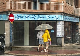 Dos personas se refugian de la lluvia con un paraguas.