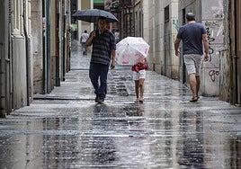 Varias personas se protegen de la lluvia.
