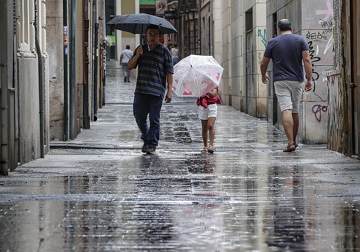 Varias personas se protegen de la lluvia.