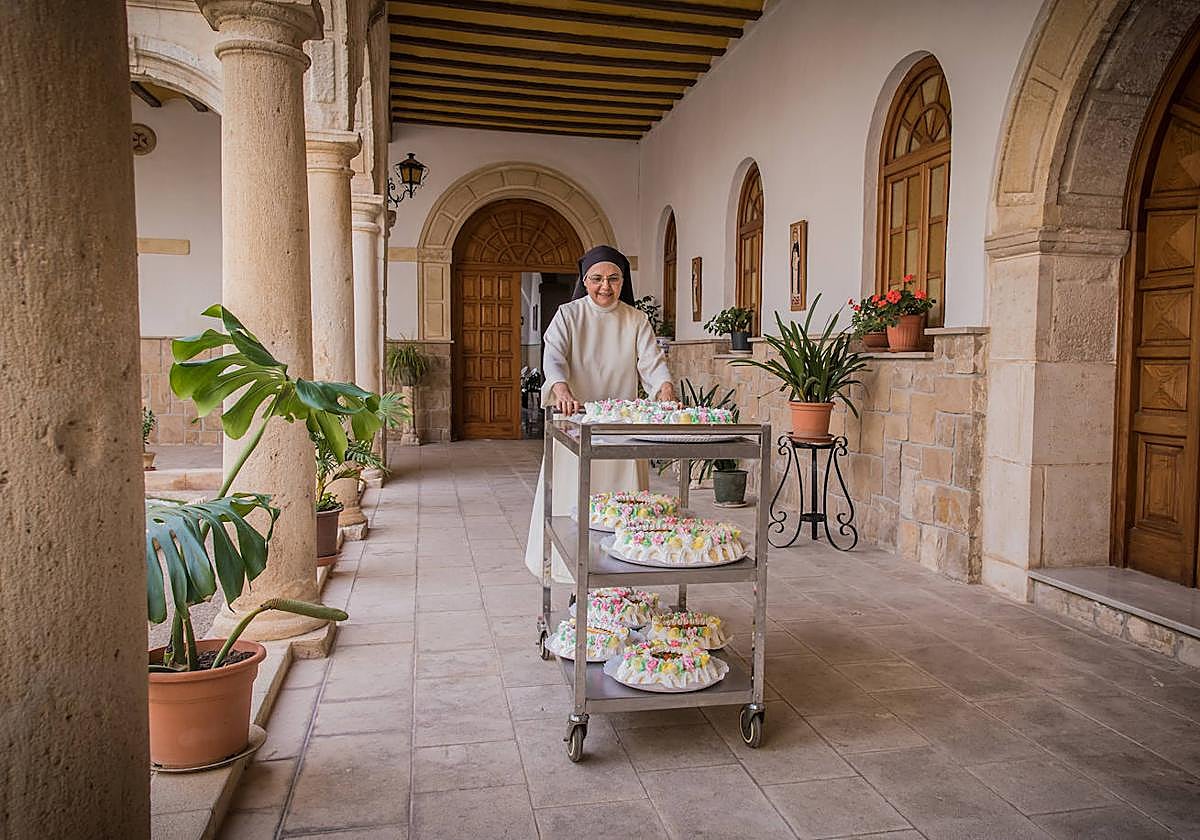 Una monja del Monasterio de la Santísima Trinidad y Santa Lucía de Orihuela muestra un conjunto de tortadas en un carrito.