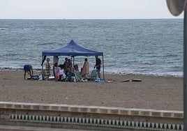 Varias personas intentan alargar el día de playa pese a la lluvia en la playa de Muchavista de El Campello.