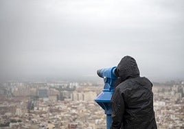 Un ciudadano observa alicante bajo la lluvia.