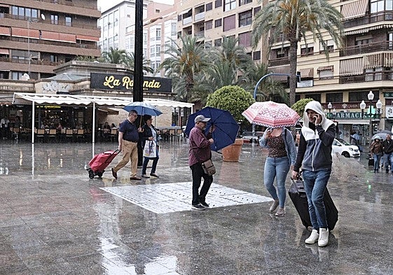 Transeúntes se protegen de la lluvia este martes en Alicante.