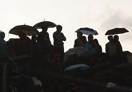 Varias personas se resguardan de la lluvia con sus paraguas.