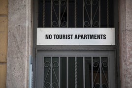 Vecinos cuelgan un cartel contra los pisos turísticos.