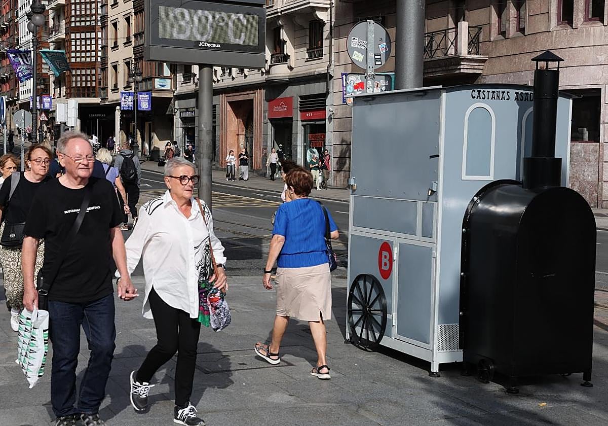 Una pareja pasa por delante de un puesto de castañas asadas.