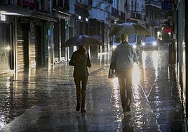 Dos personas se protegen de la lluvia con un paraguas.