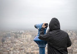 Un ciudadano observa Alicante desde las alturas bajo la lluvia.
