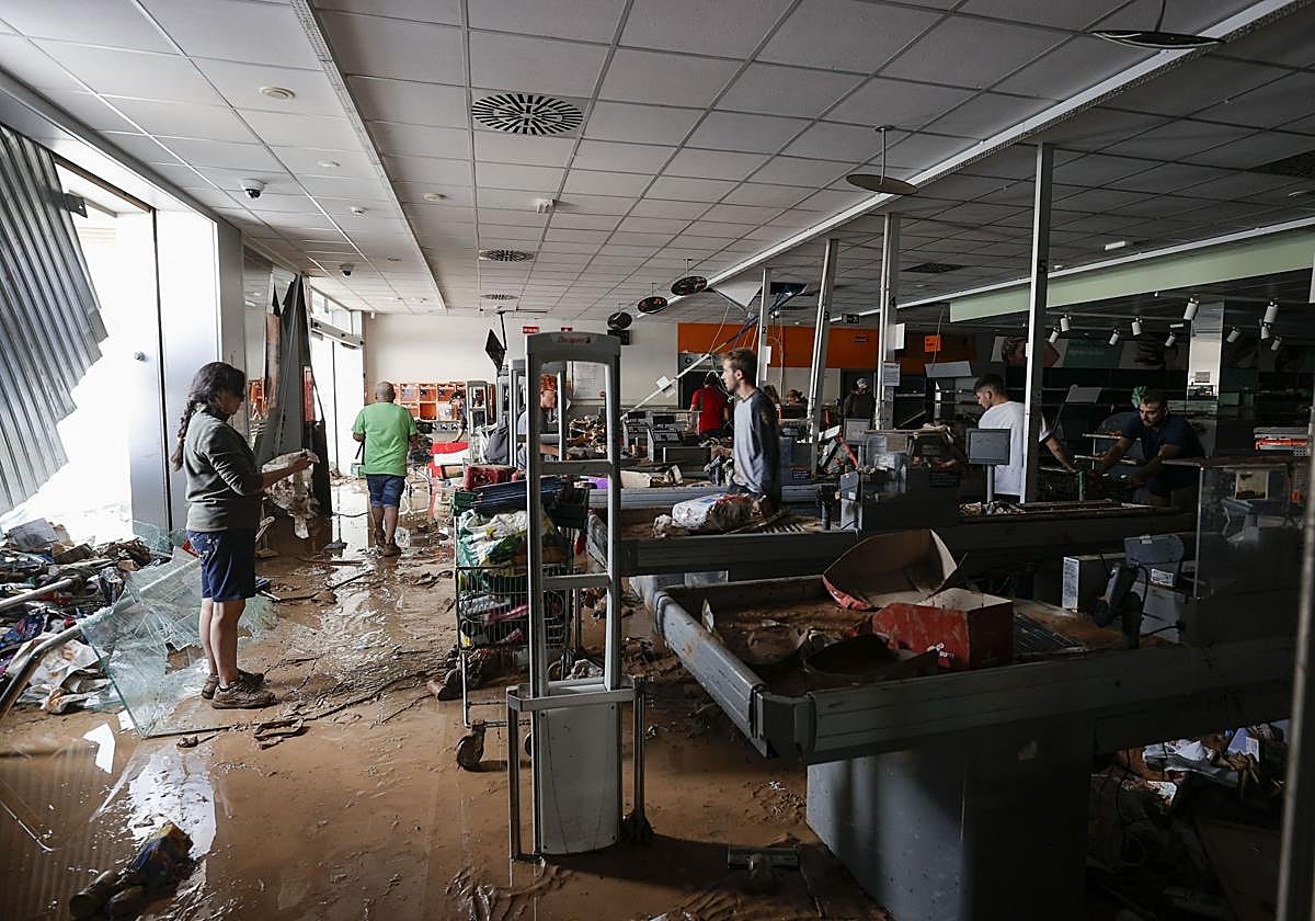 Varias personas intentan recoger alimentos de una tienda de Paiporta.