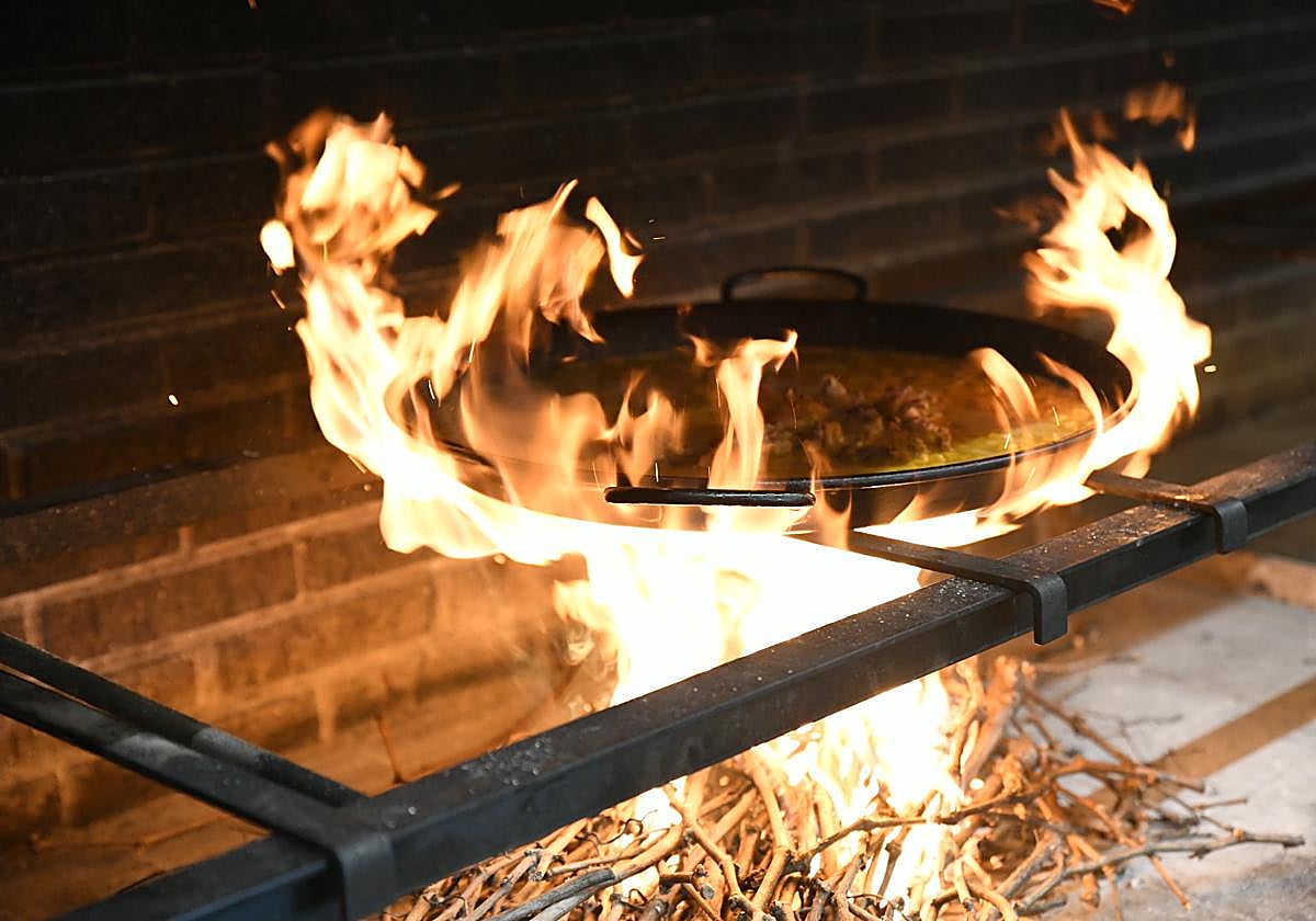 Las llamas envuelven la paella para cocinar el arroz.