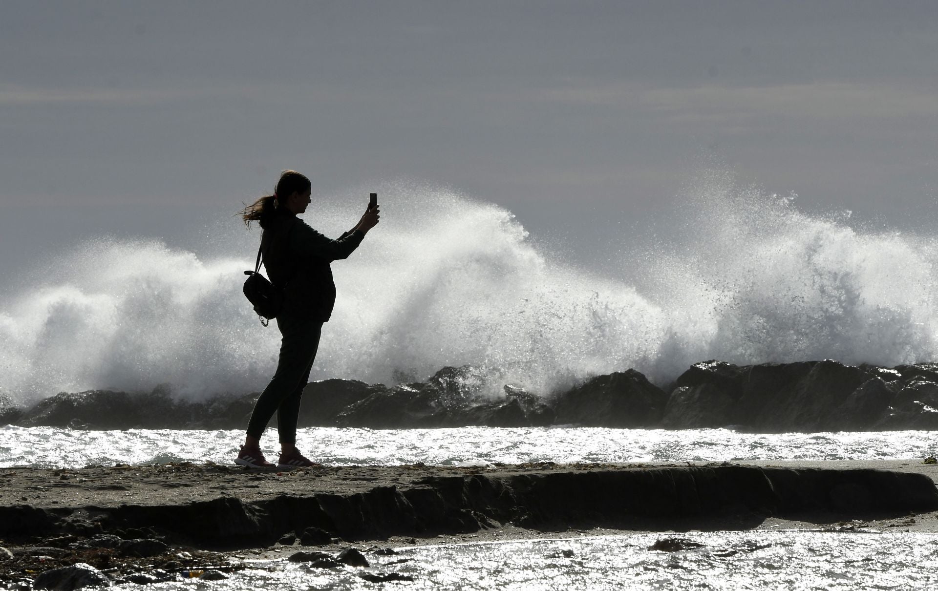 Una persona fotografía las olas producidas por el fuerte viento.