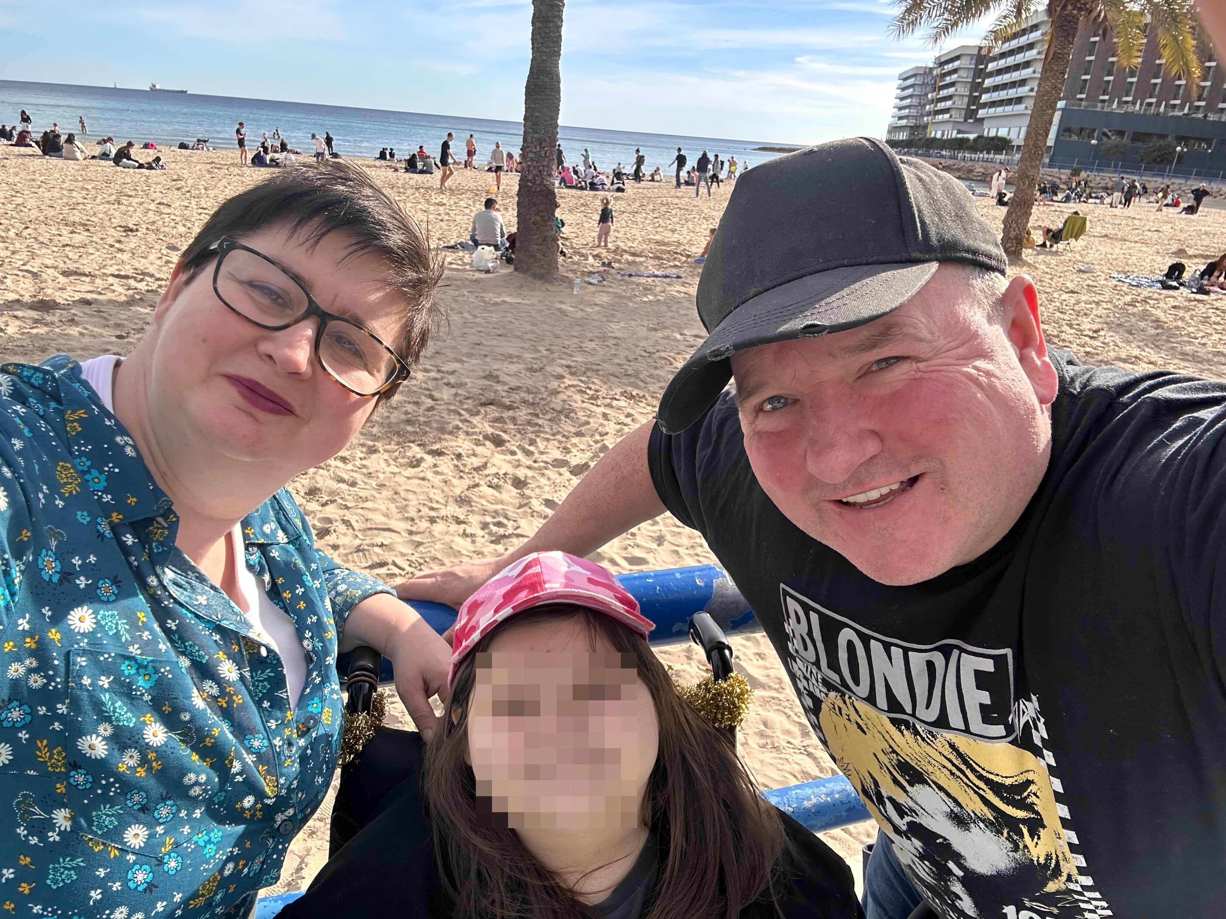 Charlotte junto a sus padres frente a la playa del Postiguet de Alicante.