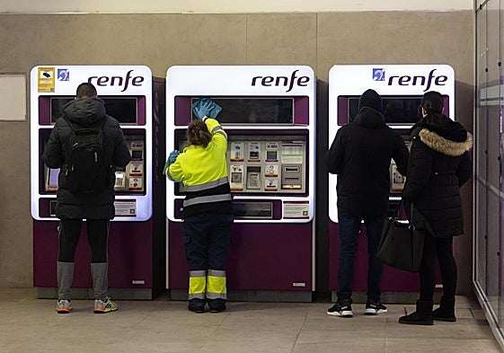 Varias personas compran billetes en una máquina de venta de billetes.