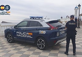 Un agente de la Policía Nacional de Benidorm junto a una patrulla.