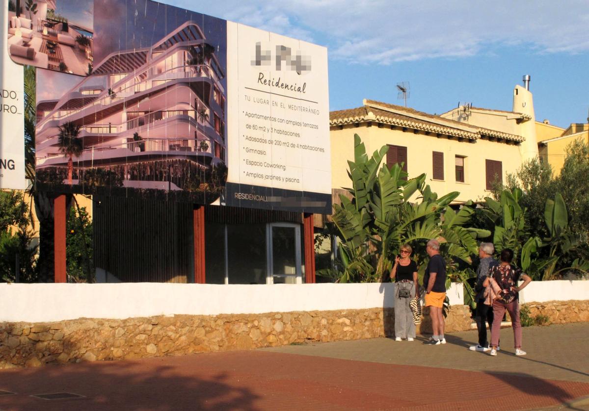 Extranjeros miran el cartel de un nuevo residencial en Dénia.