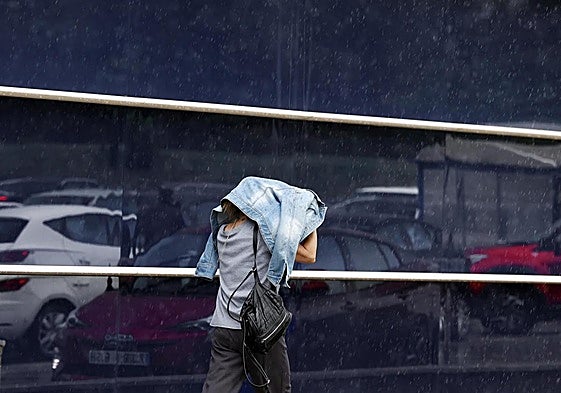 Una mujer se dirige a comprar en medio de una intensa lluvia.