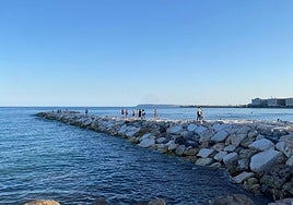 Varias personas por el nuevo espigón del Postiguet.