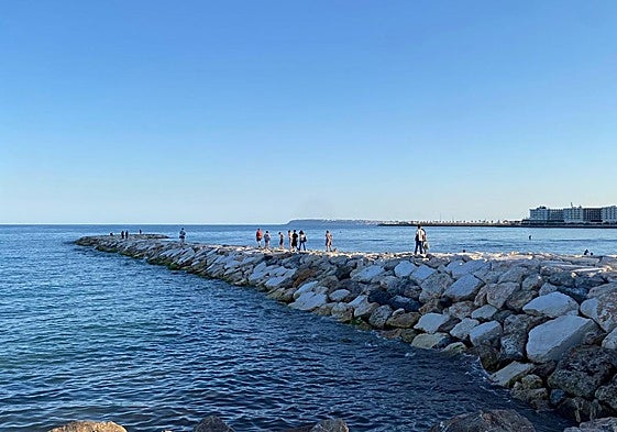 Varias personas por el nuevo espigón del Postiguet.