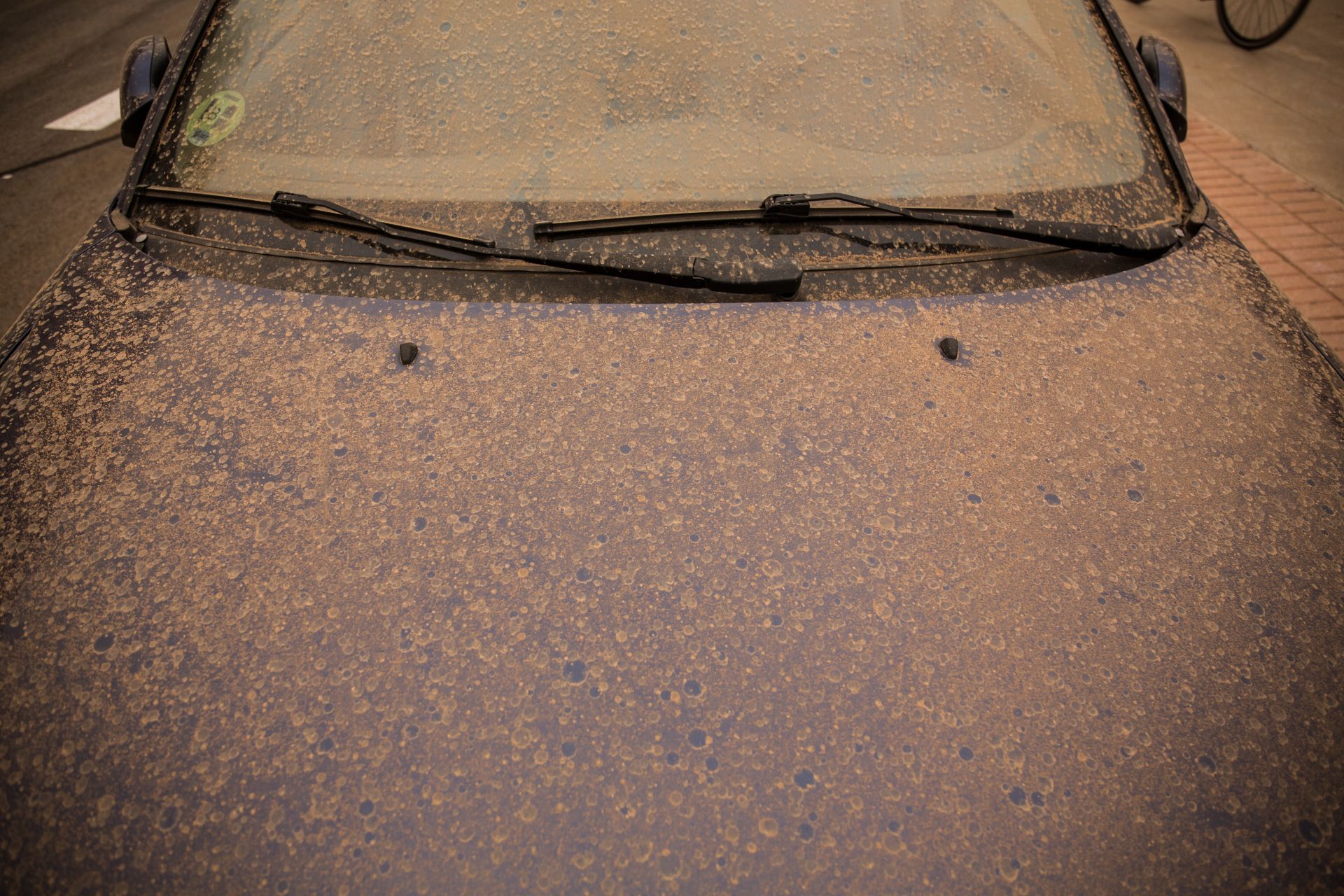 Car covered in mud after rain with haze.