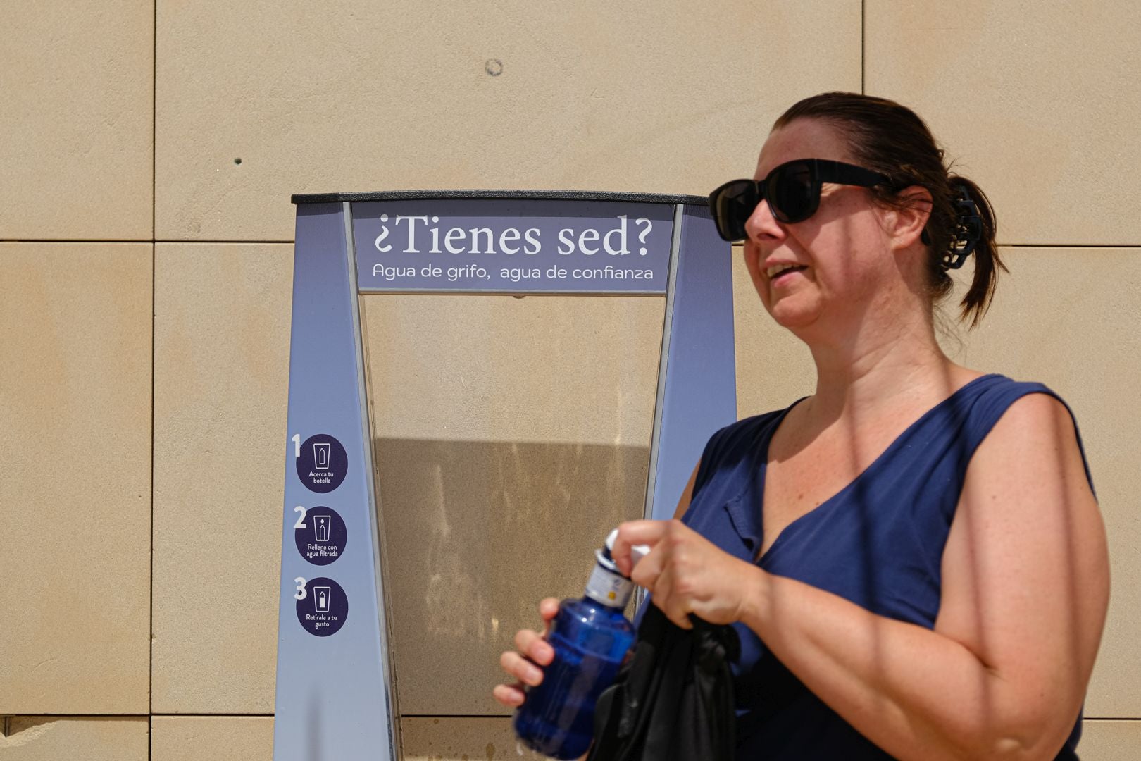 A person drinks from a fountain.