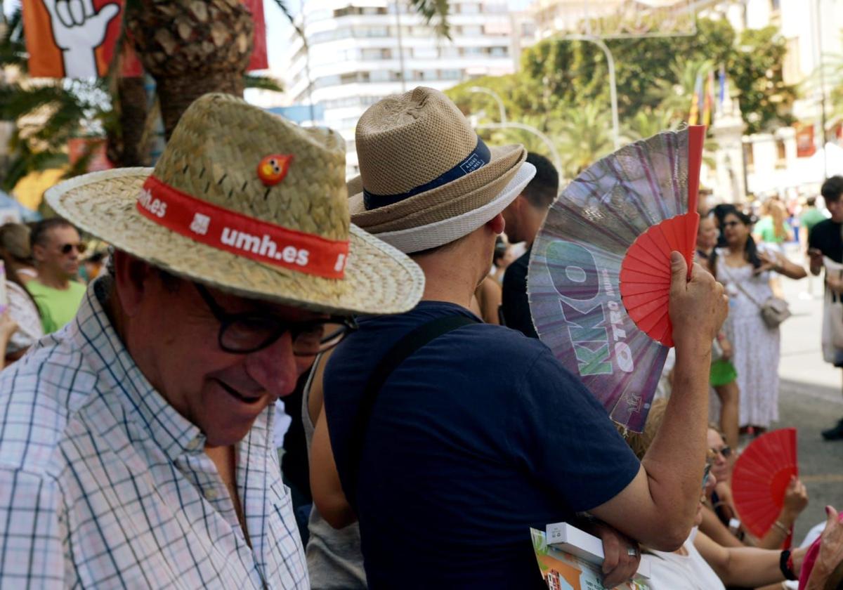 Several people shield themselves from the heat during the Hogueras mascletà.