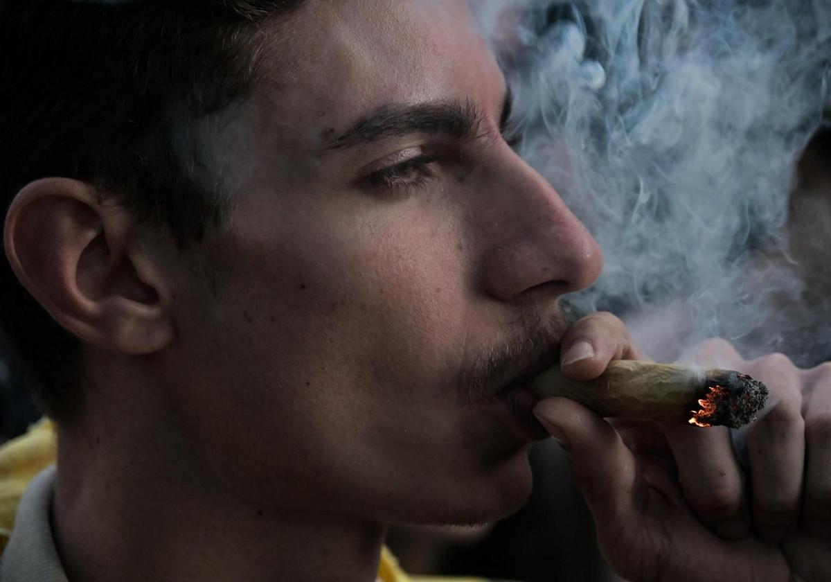 A young man smokes a marijuana cigarette.