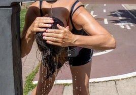 Una mujer se refresca en una fuente para combatir el calor.