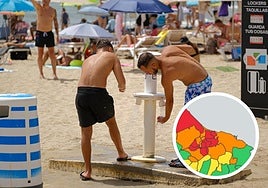Dos bañistas se refrescan en las duchas de la playa del Postiguet.