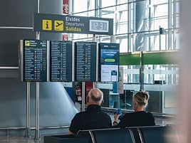 Dos turistas miran el panel de vuelos.