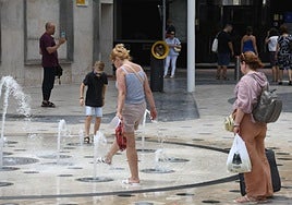 Unos turistas se refrescan en una fuente de Alicante.