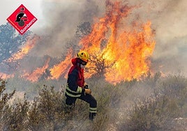 Un bombero pasa por delante de una gran llamarada en el incendio de Ibi.