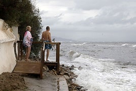 Una pareja mira el horizonte entre el temporal marítimo.