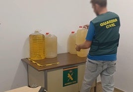 Un guardia civil con algunas de las garrafas decomisadas.