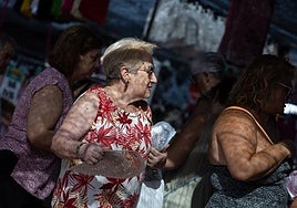 Una mujer se protege del calor con un abanico.