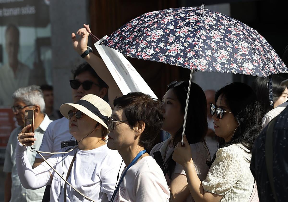 Varios turistas se protegen del calor.